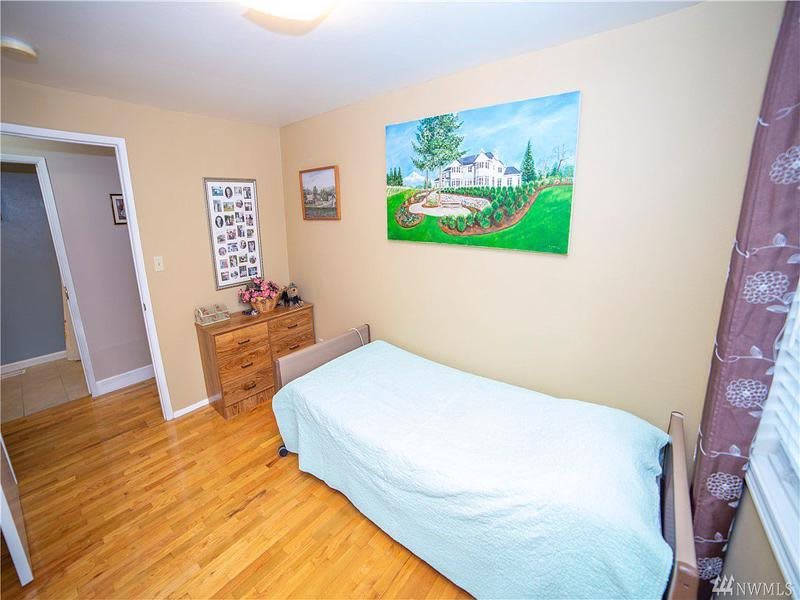 A cozy bedroom with a single bed, wooden flooring, and decorative artwork on the walls.