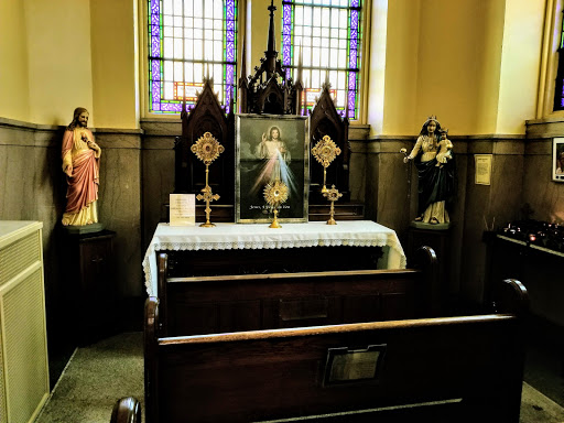 A serene interior of a church featuring an altar with religious statues and stained glass windows.