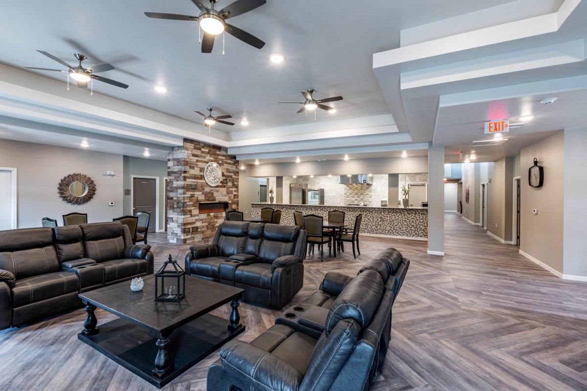 A spacious modern living room with leather seating, a stone fireplace, and an open floor plan.