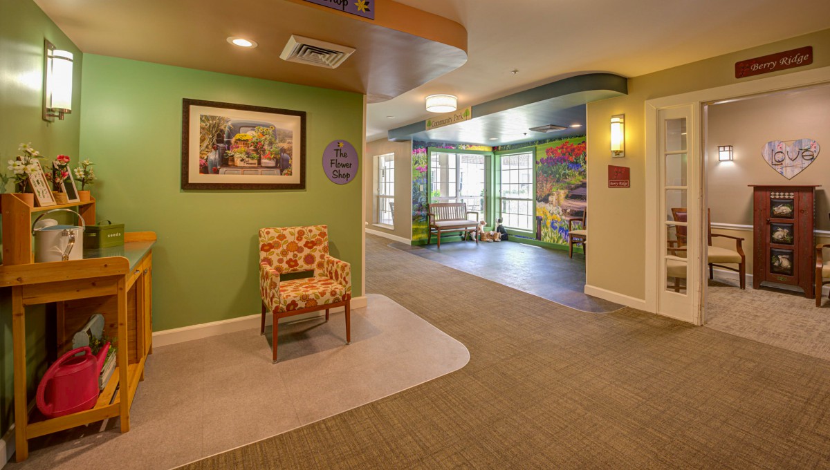 A warmly decorated lobby area featuring a floral-patterned chair, artwork on the wall, and colorful accents near large windows.