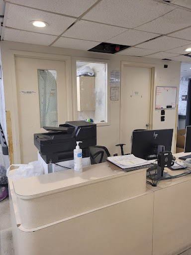 A view of an office reception area featuring a desk with a printer and computer.