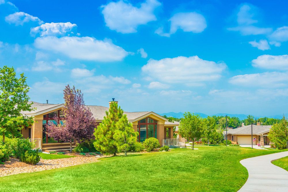 A picturesque house surrounded by lush greenery and a clear blue sky.