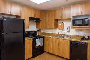 A modern kitchen featuring wooden cabinets, a black refrigerator, and an oven.