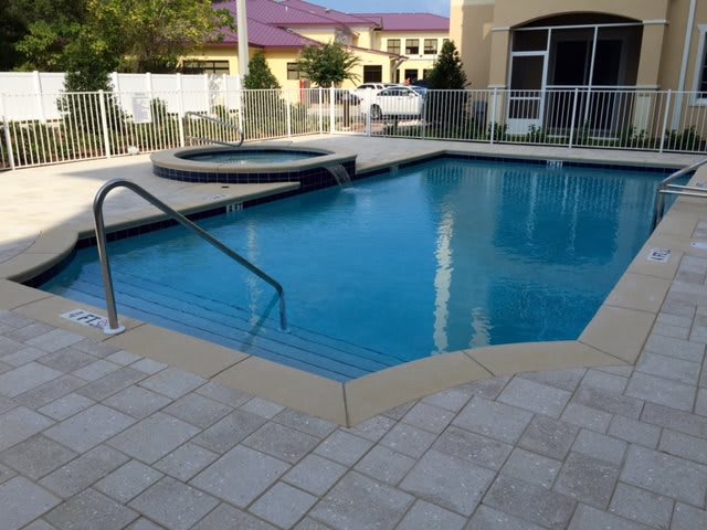 An outdoor residential swimming pool with an attached spa on a sunny day.