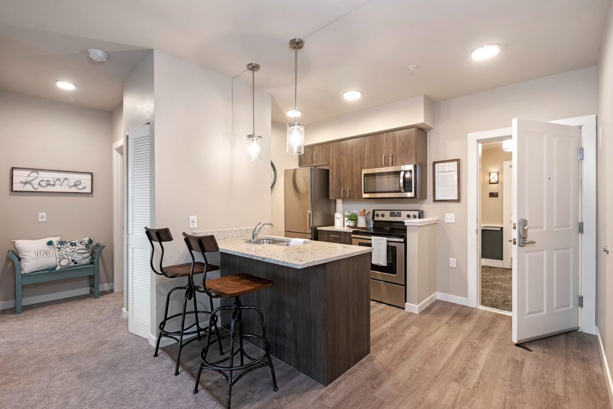 A modern kitchen with sleek appliances, an island, and stylish pendant lighting.