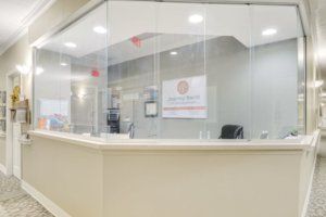 A modern office reception area with a glass partition and desk.