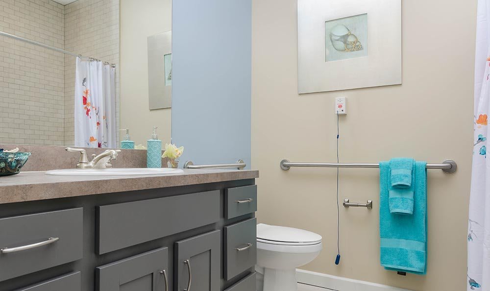 A modern bathroom with a sink, toilet, and mirror, featuring turquoise accents.