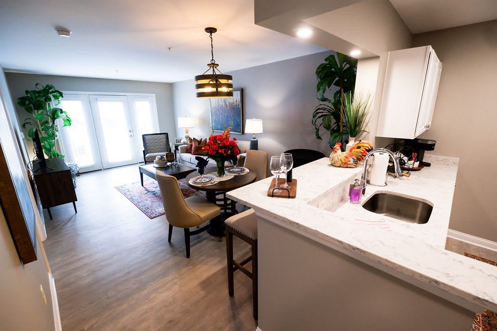 A modern open-concept living space featuring a kitchen, dining, and sitting area with stylish decor and lighting.