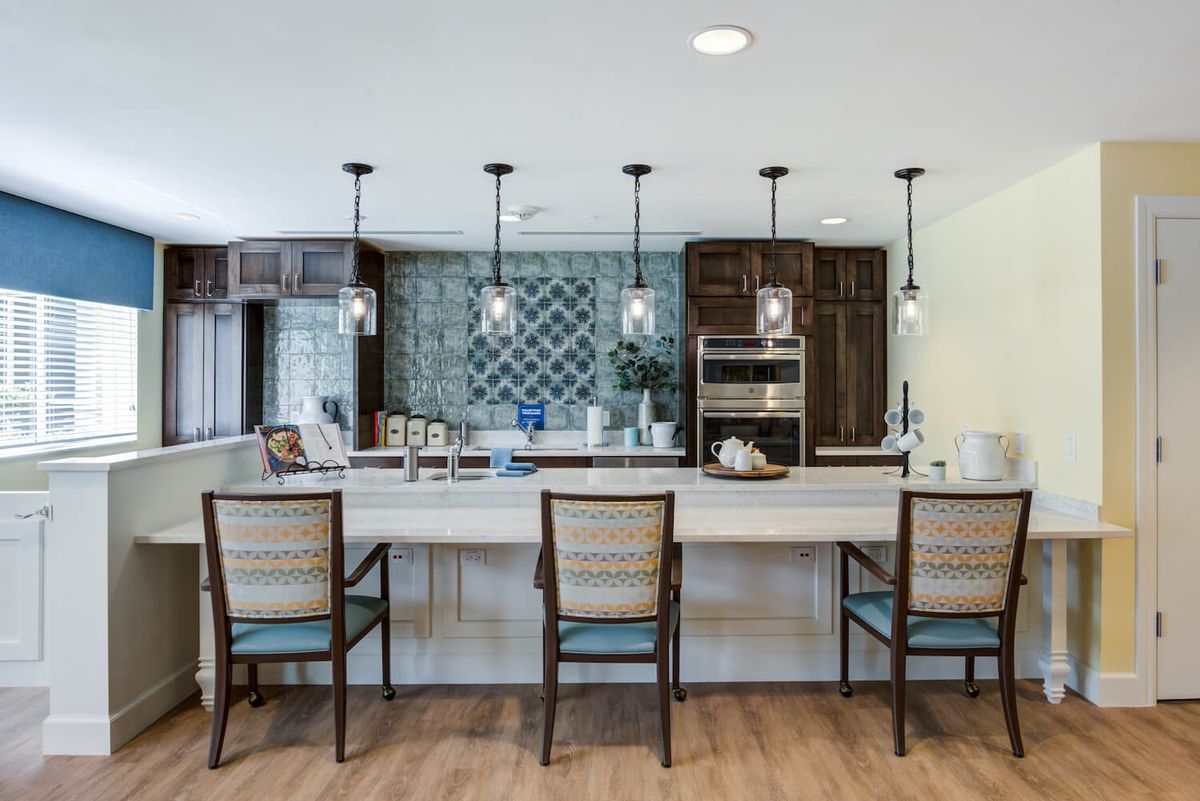 A modern kitchen with an island counter, stylish pendant lights, and a tile backsplash.