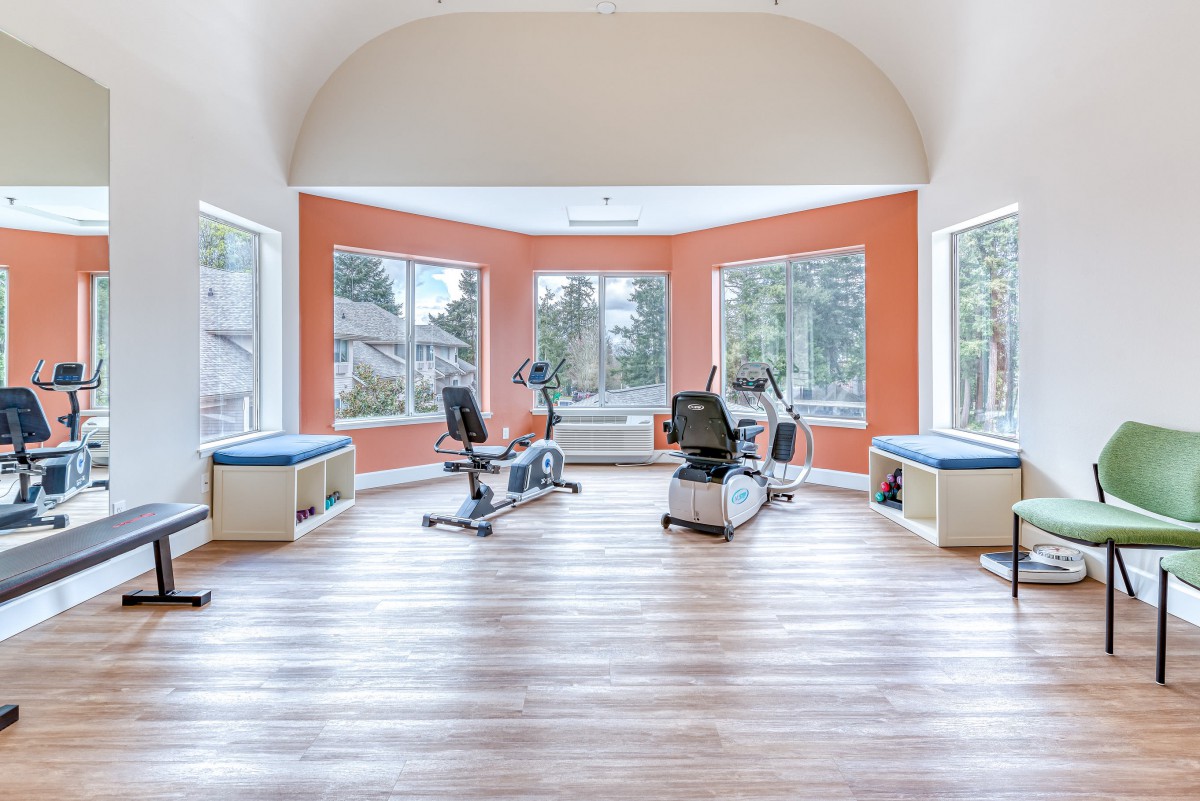 A bright and airy fitness room with exercise equipment and large windows.