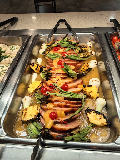 A beautifully arranged platter featuring sliced cooked meat, garnished with vegetables and fruits for an appealing presentation.