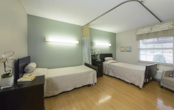 A hospital room with two neatly arranged beds and dividing curtains.