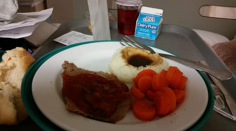 Hospital meal consisting of mashed potatoes with gravy, carrots, meat, and a carton of milk.