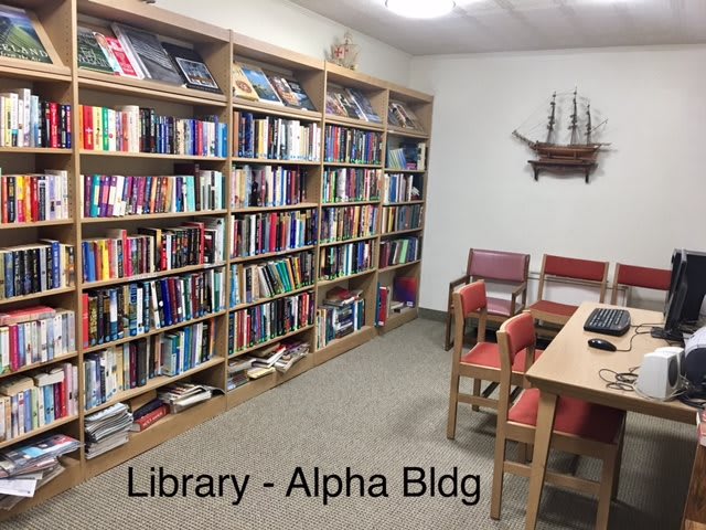 A cozy library corner with bookshelves and a small seating area in the Alpha Building.