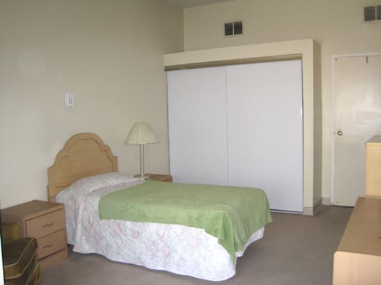 A minimalist bedroom with a single bed and a closet.