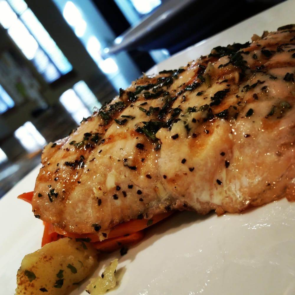 A delicious grilled salmon fillet seasoned with herbs and spices, served on a plate.