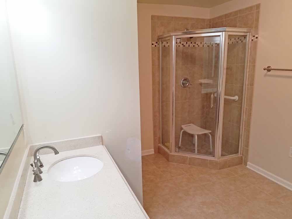 A bathroom with a corner shower and a sink countertop.