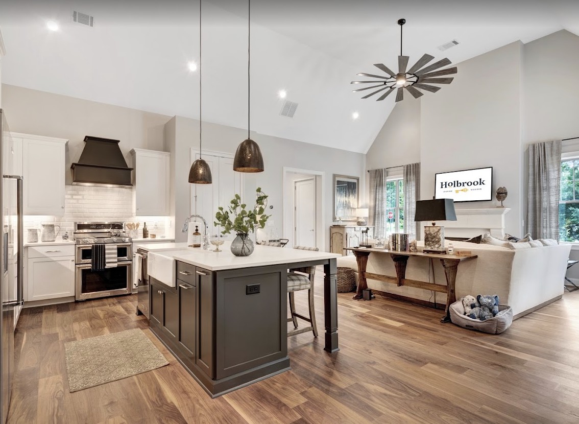 A modern kitchen with an island, pendant lights, and wood flooring.