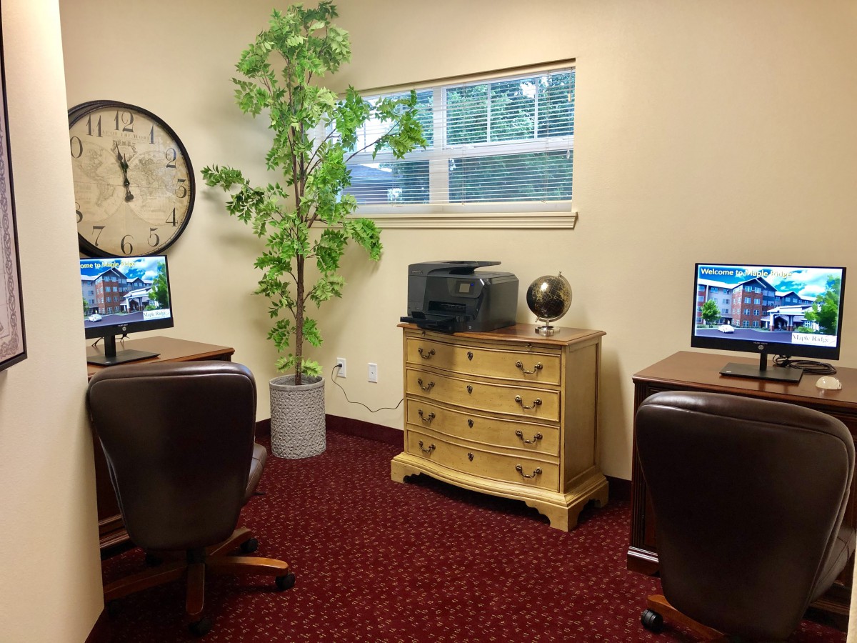 A cozy office space with two computer workstations, a printer, and decorative items.