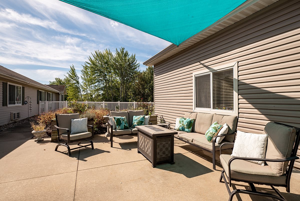 A cozy outdoor patio with comfortable seating and a sunshade.