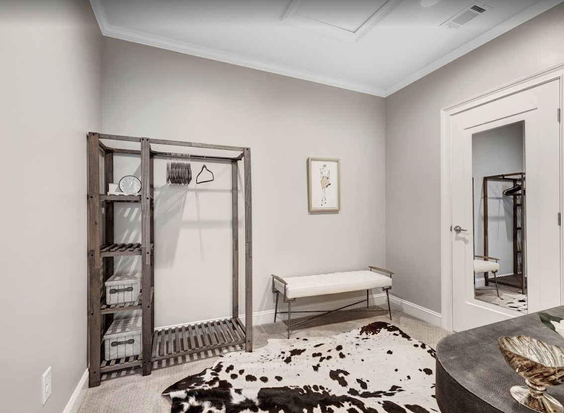 A minimalist room with an open closet, a bench, and a patterned rug.