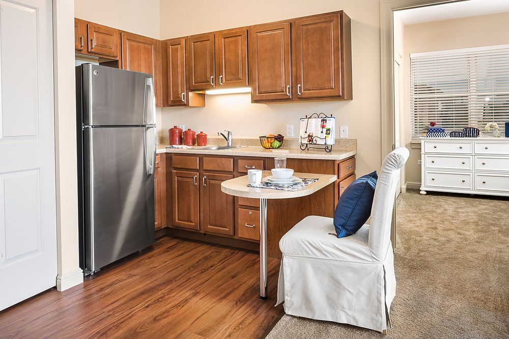 A cozy modern kitchen with wooden cabinets and a stainless steel refrigerator.