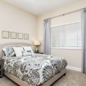 A cozy bedroom with patterned bedding and neutral decor.