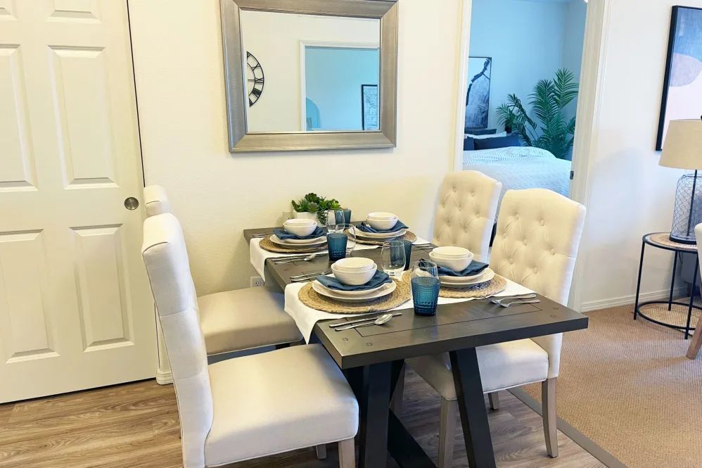 A neatly arranged dining table with elegant place settings and cushioned chairs.