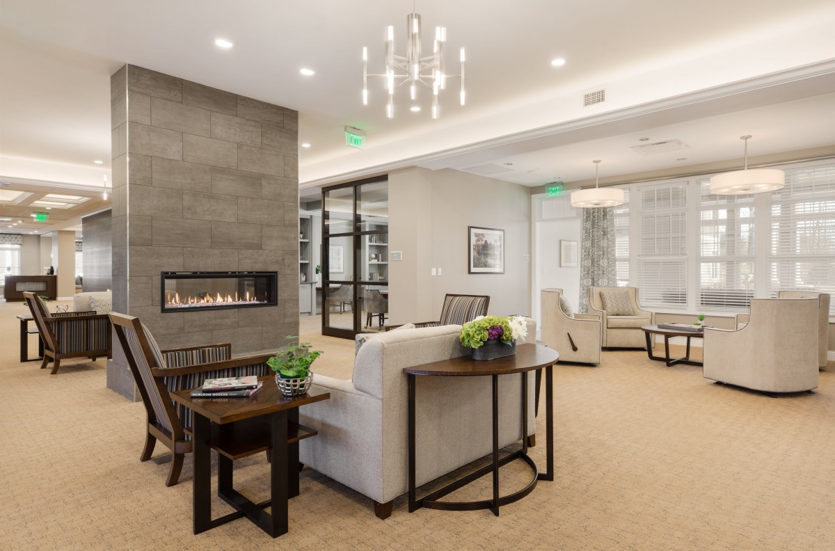 A modern living room with elegant dcor, featuring a fireplace, comfortable seating, and a stylish chandelier.