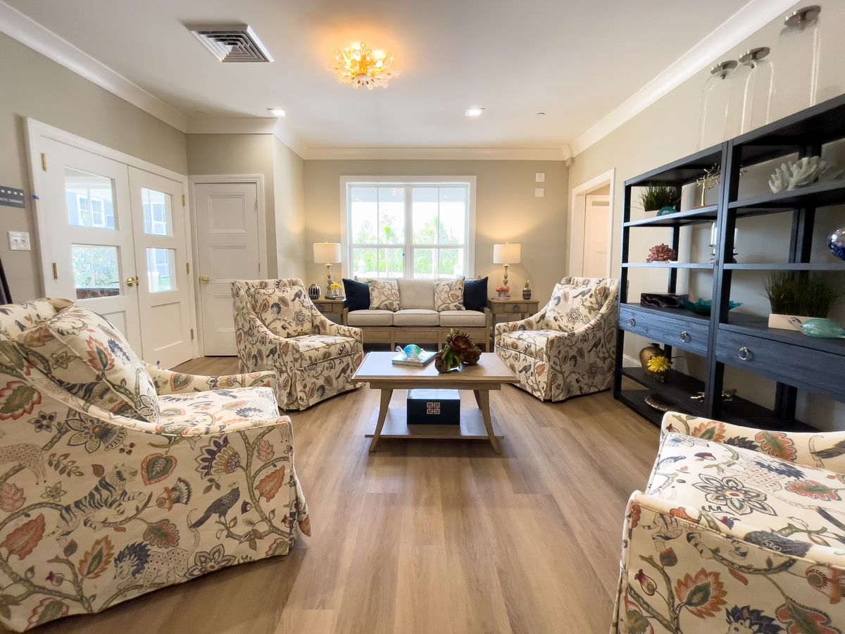 A cozy living room featuring floral armchairs, a comfortable sofa, and a central coffee table on hardwood flooring.