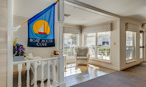 A cozy living room with ample sunlight, featuring a nautical-themed flag and a comfortable seating area.