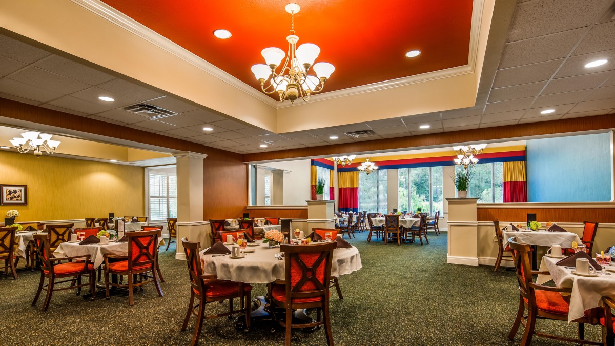 A spacious restaurant dining area with elegantly set tables and warm lighting.