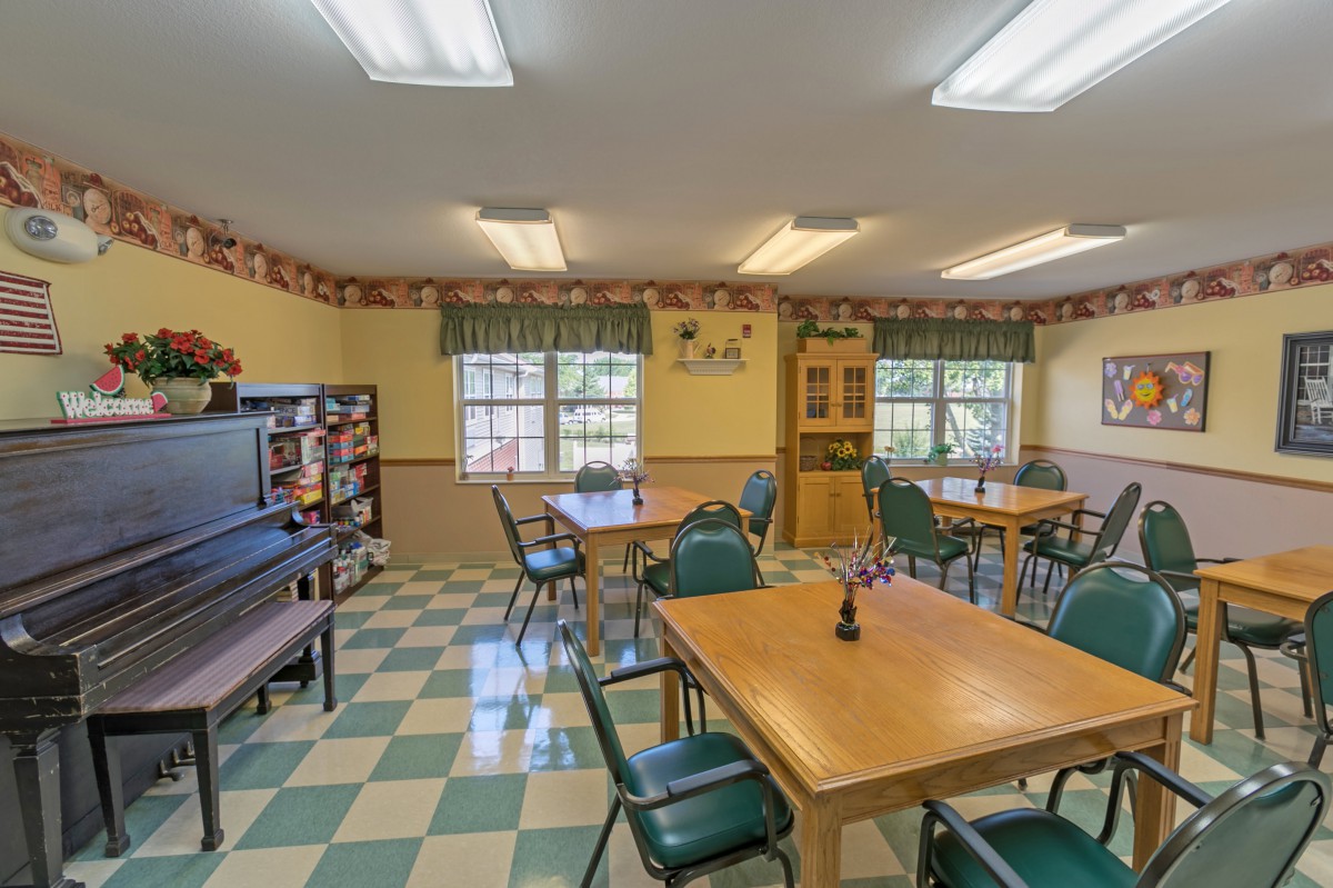 A cozy dining room with wooden tables and chairs, decorated with patterned wallpaper and tiled flooring.