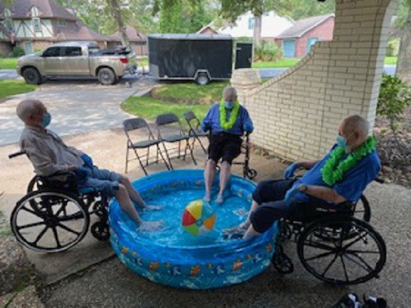 Seniors enjoy a summer day by relaxing their feet in a kiddie pool.