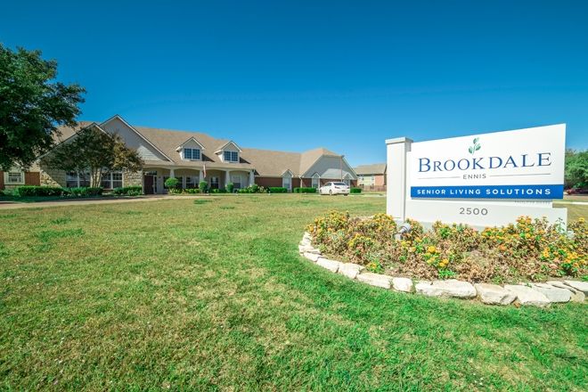 A well-maintained building with a sign and landscaped lawn beneath a clear blue sky.
