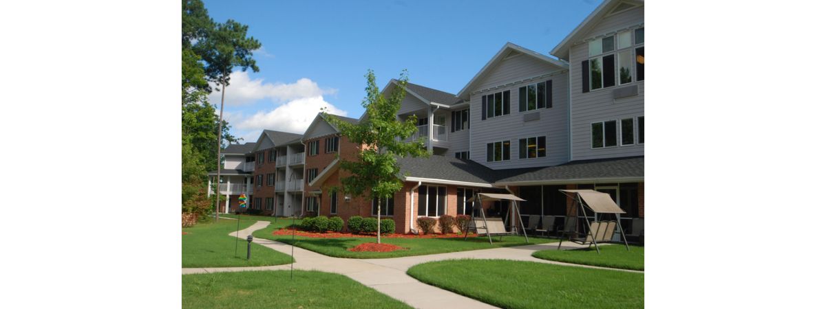 A residential apartment building with well-maintained landscaping in a suburban area.