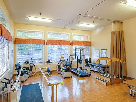 A well-lit gym with various exercise machines and treadmills.