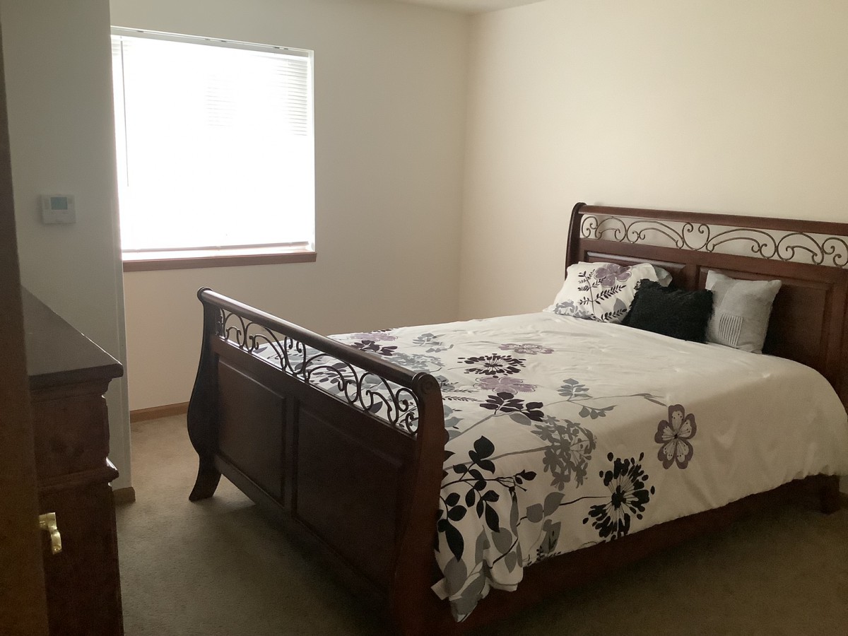 A cozy bedroom with a wooden bed frame and floral bedding.
