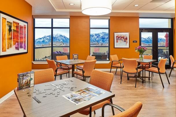 A modern dining area with orange walls and large windows showcasing a scenic mountain view.