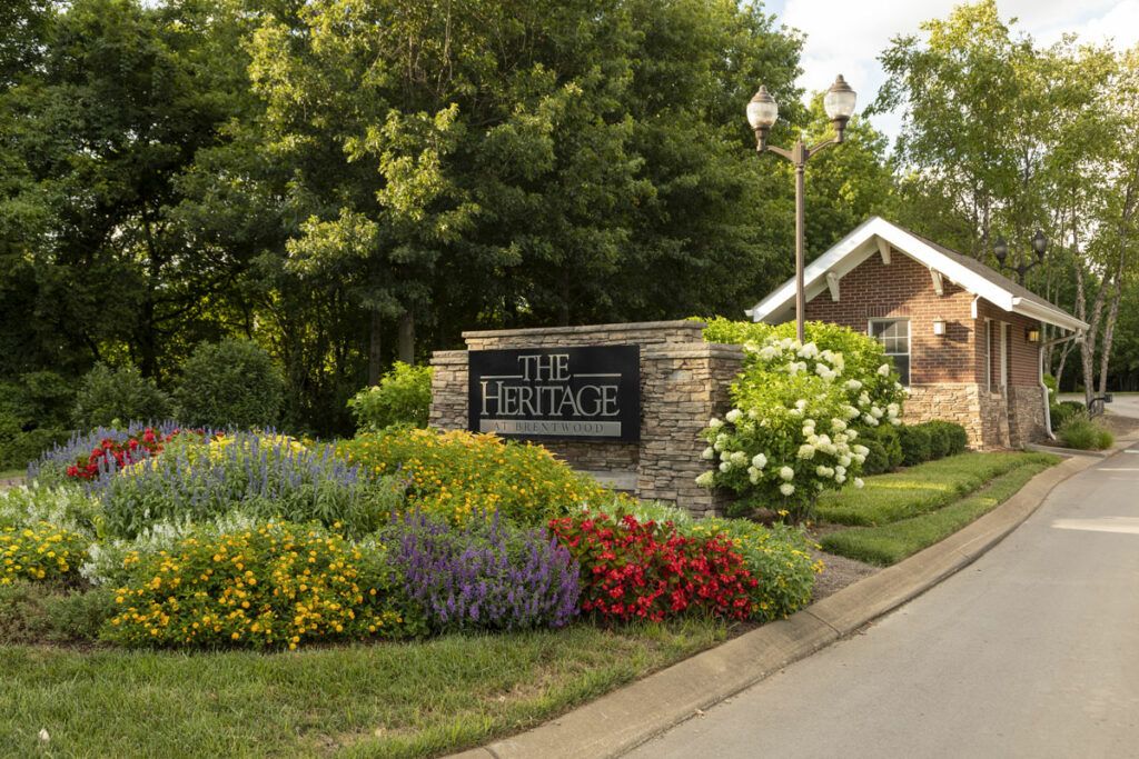 Beautifully landscaped entrance with a sign surrounded by colorful flowers and greenery.