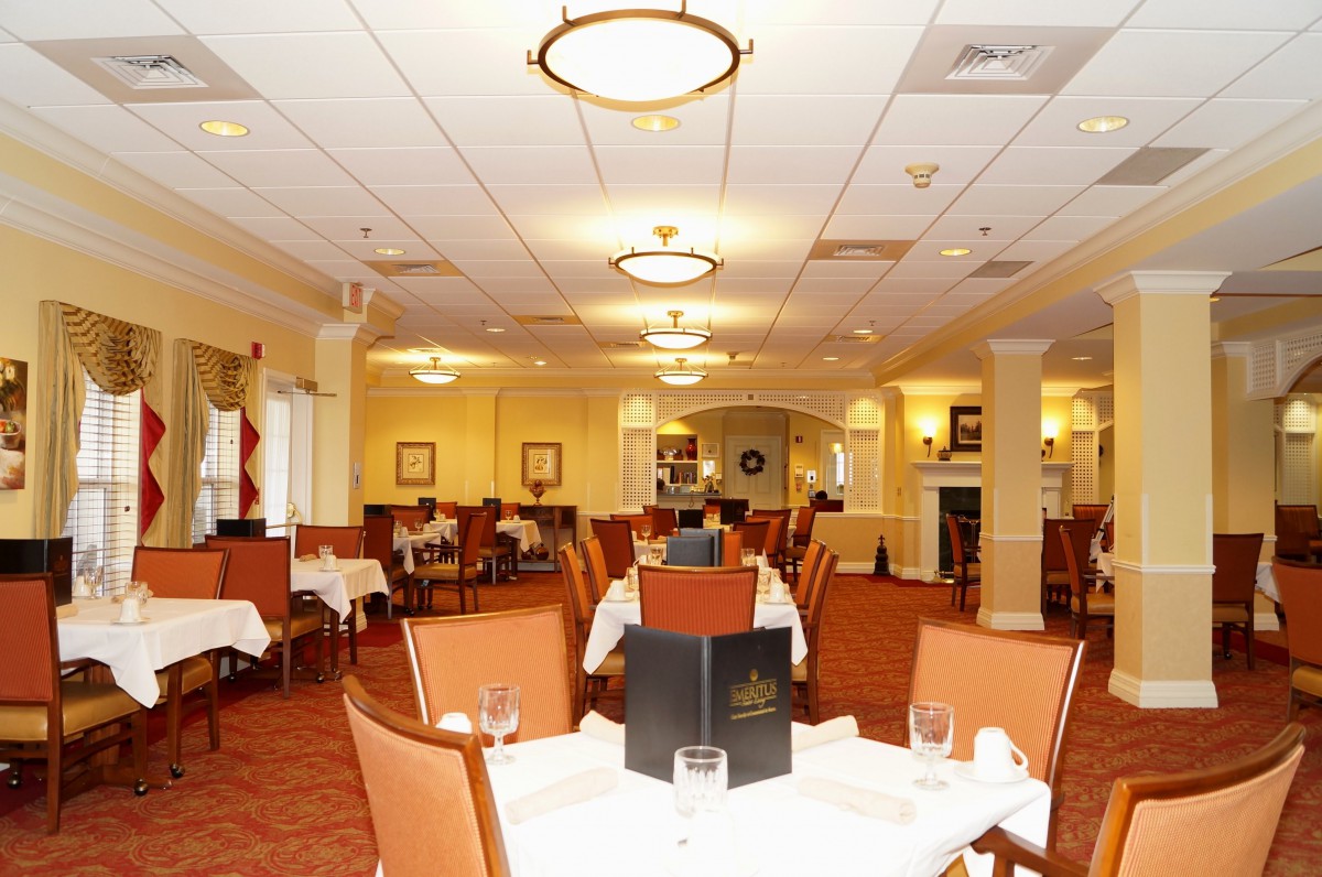 An elegant restaurant dining area with neatly arranged tables and chairs, soft lighting, and a menu placed on one of the tables.