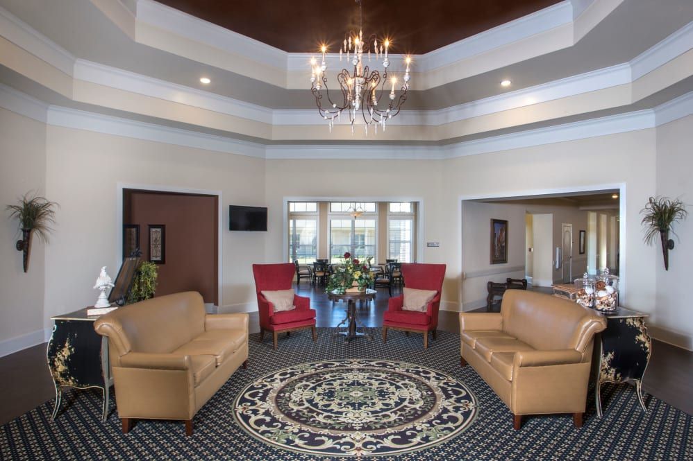 A spacious, well-lit living room featuring elegant furniture and a central chandelier.