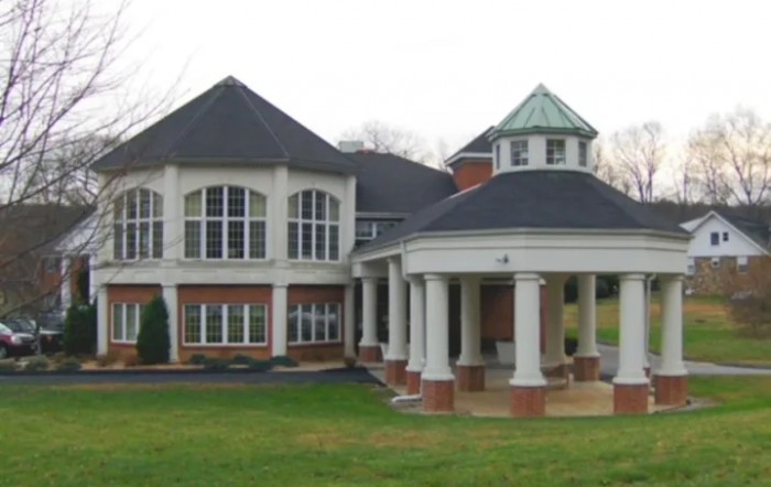 A large house with prominent columns and a spacious lawn.