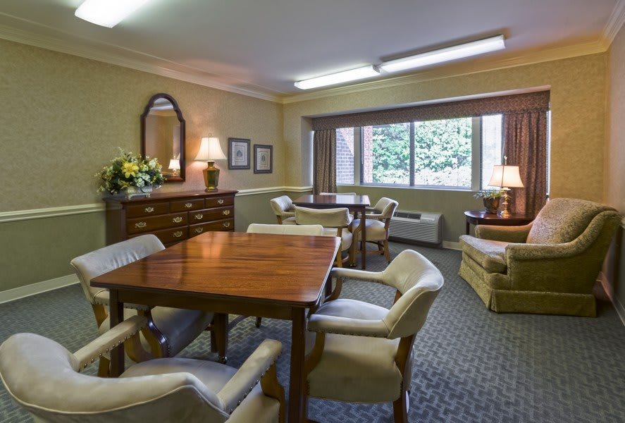 A cozy living room with comfortable chairs and tables, featuring warm lighting and elegant decor.