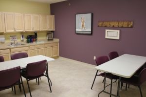 A break room featuring tables, chairs, cabinetry, and wall art.