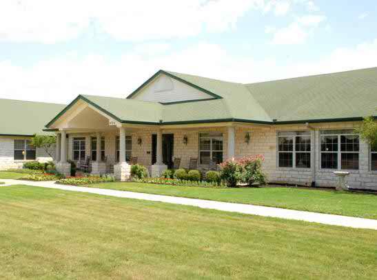 A single-story house with a green roof and a well-maintained lawn.