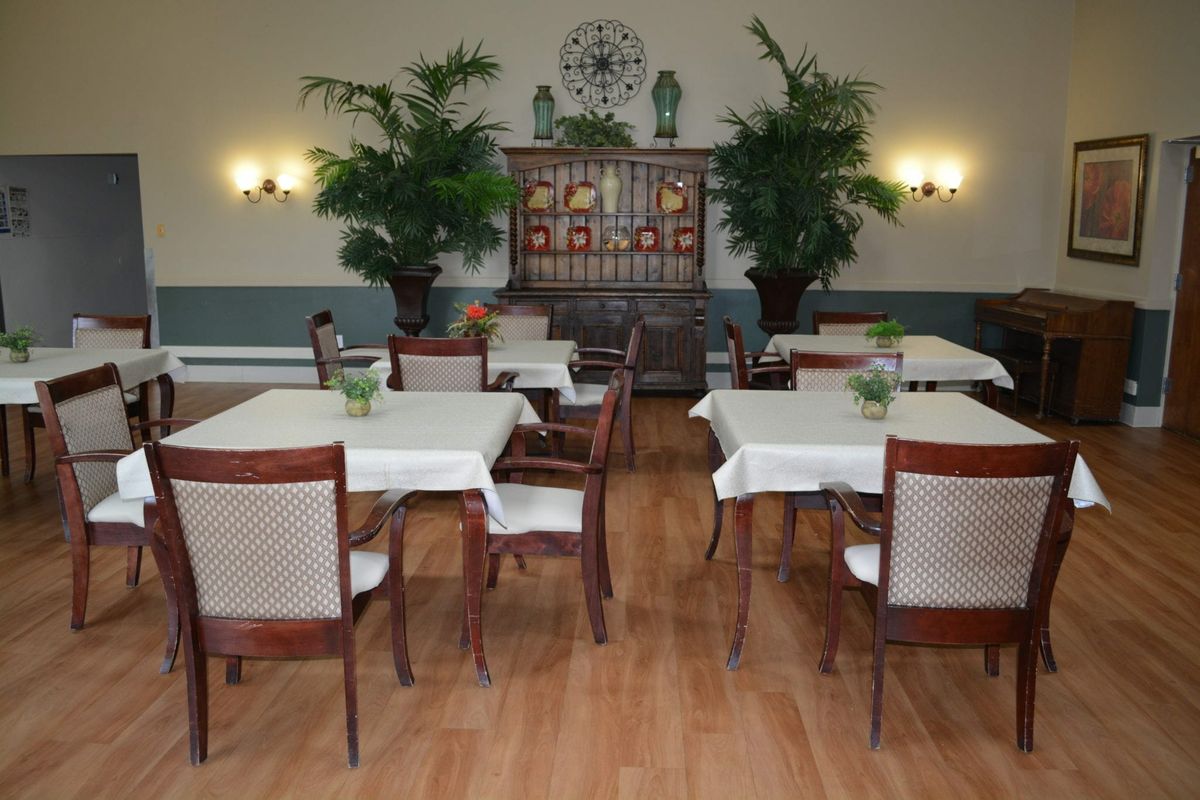 A well-decorated dining area with tables and chairs, adorned with plants and subtle lighting.
