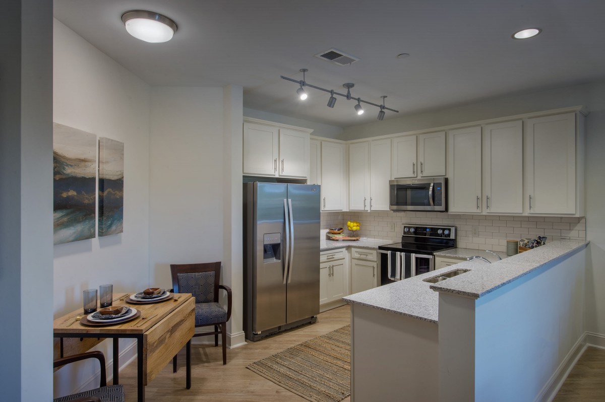 A modern kitchen with stainless steel appliances and a small dining area.