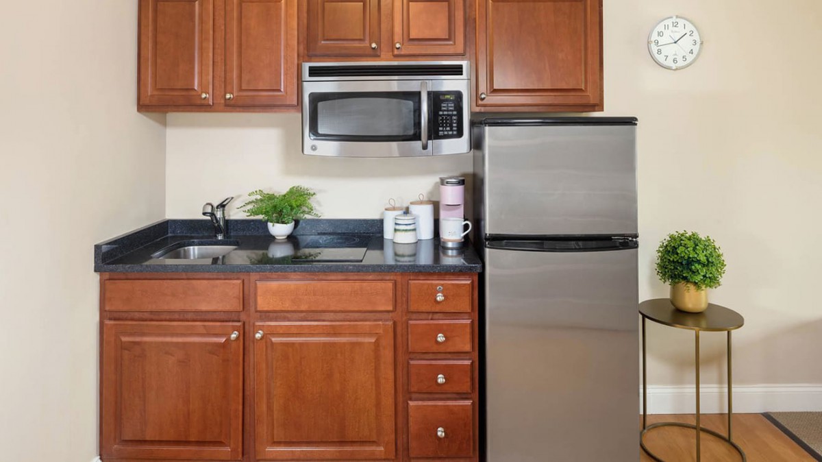 A modern kitchen with wooden cabinets, a stainless steel refrigerator, and a microwave above the counter.