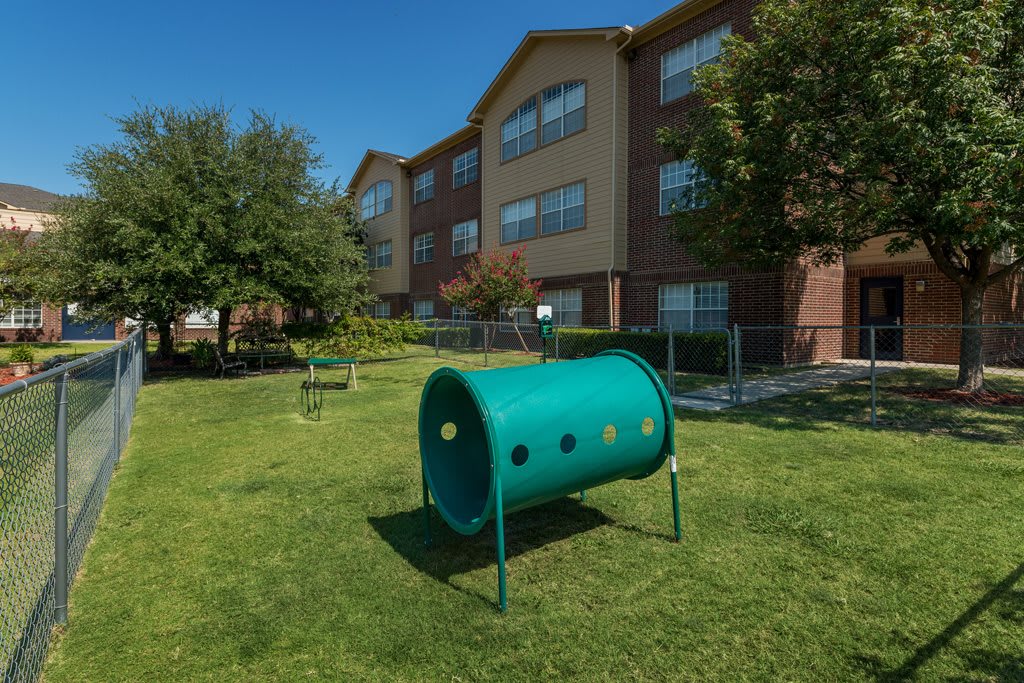 An apartment building with a green outdoor area featuring playground equipment.